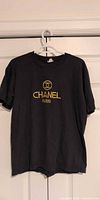Front view showing gold embroidered CHANEL PARIS logo on black T-shirt