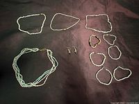 All jewellery pieces laid out: triple-strand necklace, three chokers, six bracelets, pair earrings
