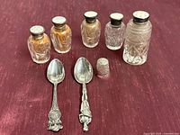 Group shot of both sterling spoons, thimble, and five cut crystal jars with metal lids