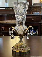 Front view of pinwheel cut crystal vase on brass base with hanging prisms