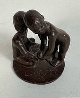 Full view of bronze sculpture showing both children and base signature