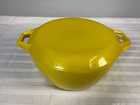 Side view of yellow enameled cast-iron casserole with lid on, showing overall form and handles