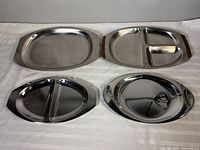 Four stainless steel trays laid out for size and style comparison