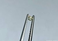 Diamond held in tweezers, side view shows brilliance