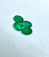Four oval emerald cabochons on white background