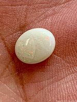 Oval cabochon white opal showing iridescent flashes