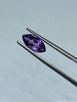 Gemstone held by tweezers side view