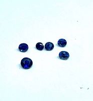 Six royal blue faceted gemstones on white background