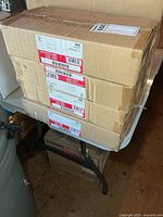 Three stacked sealed Lightolier labelled boxes on table