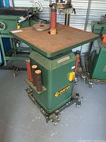 Front view of Craftex spindle sander showing table, spindle, extra sleeves and mobile base