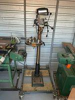 Full view of drill press on wheeled base with vise attached