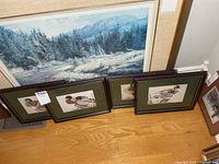 Four framed duck prints leaning against wall