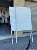 Both pegboard panels standing against storage unit showing size difference and uprights