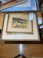 Overall view of stacked framed prints, dog print on top