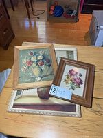 Three framed artworks stacked on table