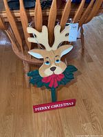 Full view of painted wooden reindeer display showing stake, reindeer head, holly, and Merry Christmas sign
