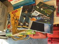 Stack of seven softcover books showing Star Wars, NASA booklet and others