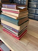 Full stack of approx. 10 vintage books on tabletop