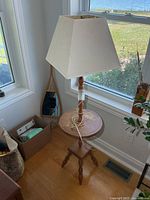 Full view of wood floor lamp with shade beside window