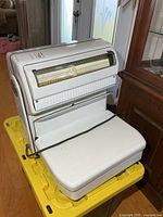 Front view of white vintage computing scale on yellow bin