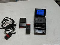 Recorder with screen raised, battery, charger and cable laid out