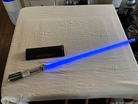 Lightsaber extended on table beside wall mount bracket