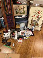 Overall lot showing framed art, easels, storage bin and assortment of supplies on floor