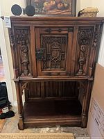Frontal view of carved hardwood cabinet hutch showing door, carvings, and lower shelf