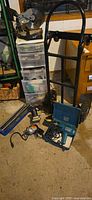 Group shot of chop saw on organizer, hand truck, tile cutter, drills, sander