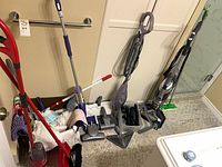 Overview of lot showing broom, mop, dustpan, accessory basket, Shark steam mop and Bissell CrossWave
