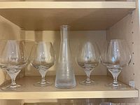 Shelf with four crystal snifter glasses and frosted bud vase