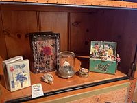 Shelf view showing green Toy Symphony trunk music box among other items