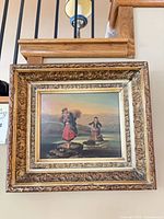 Front view of framed artwork showing image of two figures and ornate frame