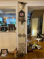 Full view of wall with mask, frame, shelf, cast iron pieces, birdhouse, gate and plaster corbels