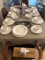 Entire dinnerware set arranged on table with silver tray, crystal vase, mugs, bowls, plates visible