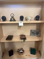 Overall view of shelf showing skulls, bell, teacup, plaque, books and teapot
