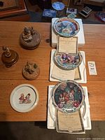 Lot overview showing two Thorens musical figurines, one children illustration plate, three Wizard of Oz plates with COAs