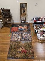 Overall lot showing three tapestries laid on floor and mirror leaning on wall