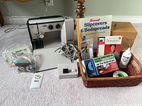 Overall lot view showing sewing machine, pedal, basket of accessories, manuals, wooden box