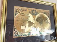 Front view of framed double-hemisphere world map print in gold frame