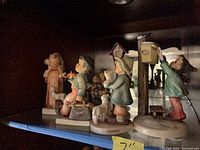 Group view of six Goebel Hummel figurines on shelf