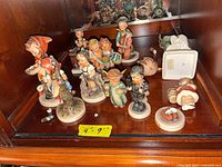 Group of Hummel figurines on shelf with size note