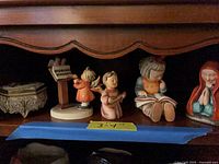 All five items on shelf: three Hummel figurines, Madonna statuette, trinket box