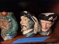 Three Royal Doulton Toby jugs on shelf