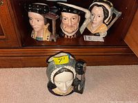 Four Royal Doulton character jugs displayed, Henry VIII and three wives