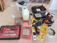 Overall lot showing socket set, drill in case, rotary tool kit, glue gun, level, glue sticks, hinges, wood finials, plastic funnels