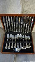 Open wooden case showing full set of cutlery pieces
