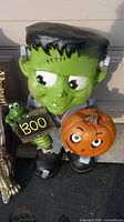 Front view of Frankenstein statue with BOO sign and pumpkin