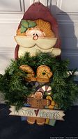 Full view of wooden Santa decoration with greenery and sign