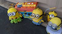 Four Minion figures and storage box on driveway